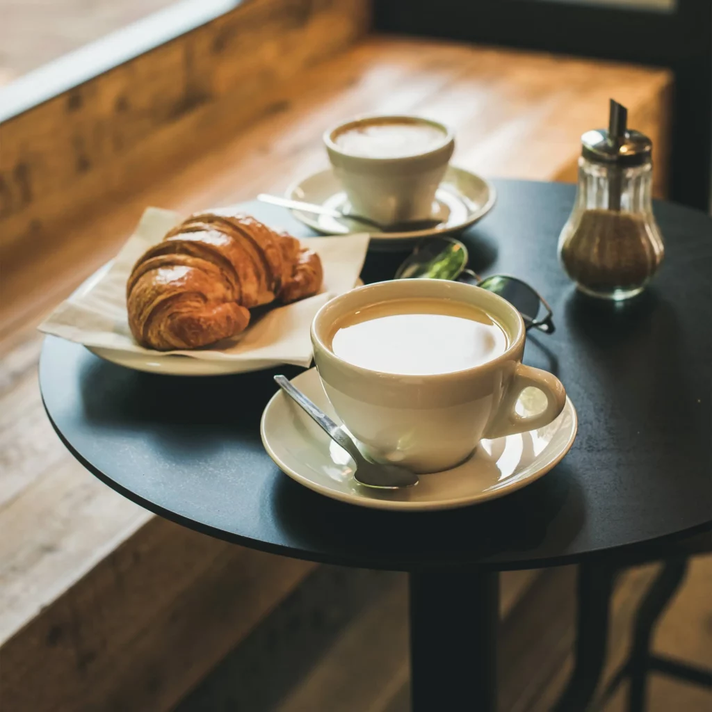 schwarzer kleiner kaffeetisch miit zwei kaffee einem crossant in der google my business agentur um google unternehmensprofil optimieren lassen