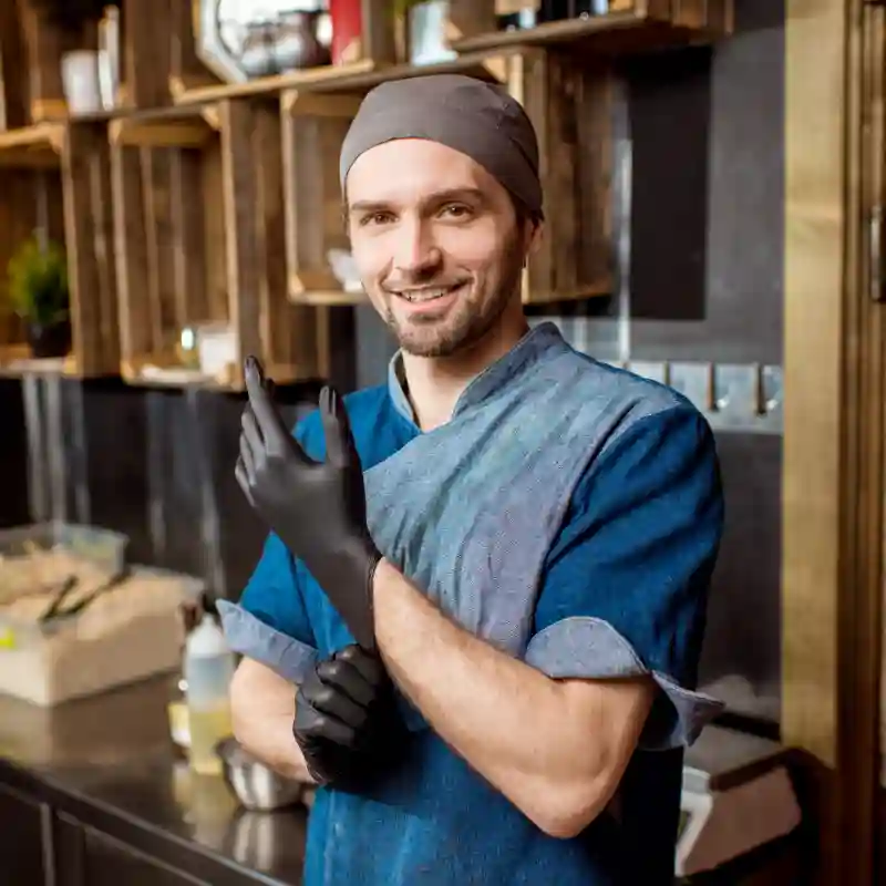 Küchenchef mit Tuch auf dem Kopf und schwarzen Handschuhen stehend vor einer Küchenwand um google unternehmensprofil optimieren lassen
