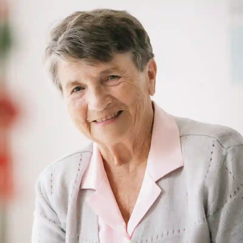 Ältere Frau als Portrait mit rosa Hemd und grauer Strickjacke um google unternehmensprofil optimieren lassen