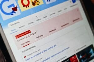 Google My Business optimieren - Eine Nahaufnahme eines Tablet-Bildschirms, auf dem eine Google-Suchergebnisseite für „Coronavirus“ angezeigt wird. Auf dem Bildschirm wird in Rot eine COVID-19-Warnung angezeigt, mit Abschnitten für einen allgemeinen Überblick, Symptome und Prävention unter der Überschrift „Coronavirus (COVID-19)“. Local SEO Agentur.