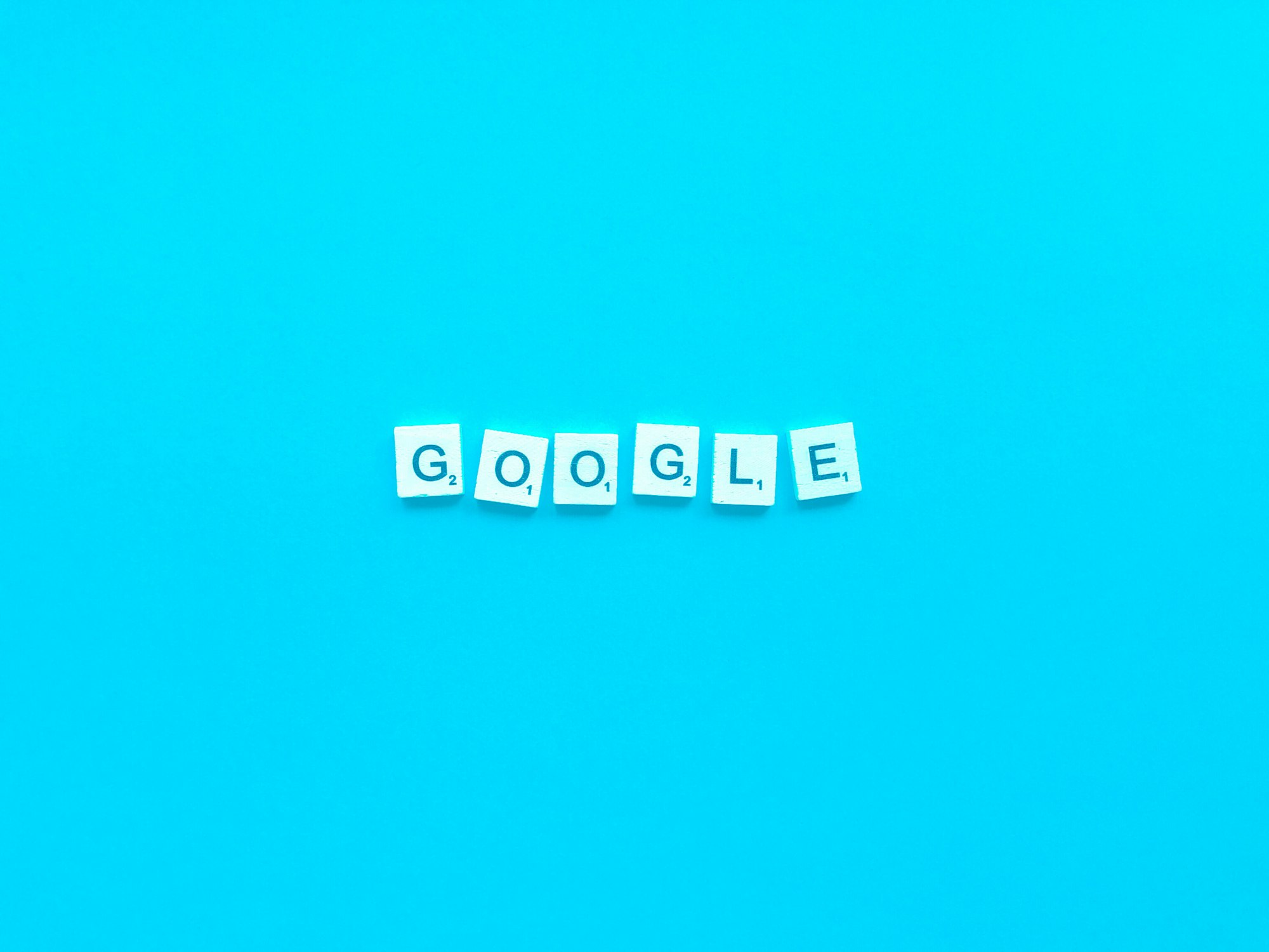 Google My Business optimieren - Sieben Scrabble-Steine bilden auf hellblauem Hintergrund das Wort "Google Unternehmenskonto". Jeder Stein enthält einen einzelnen Großbuchstaben und in der unteren rechten Ecke einen Punktwert. Local SEO Agentur.